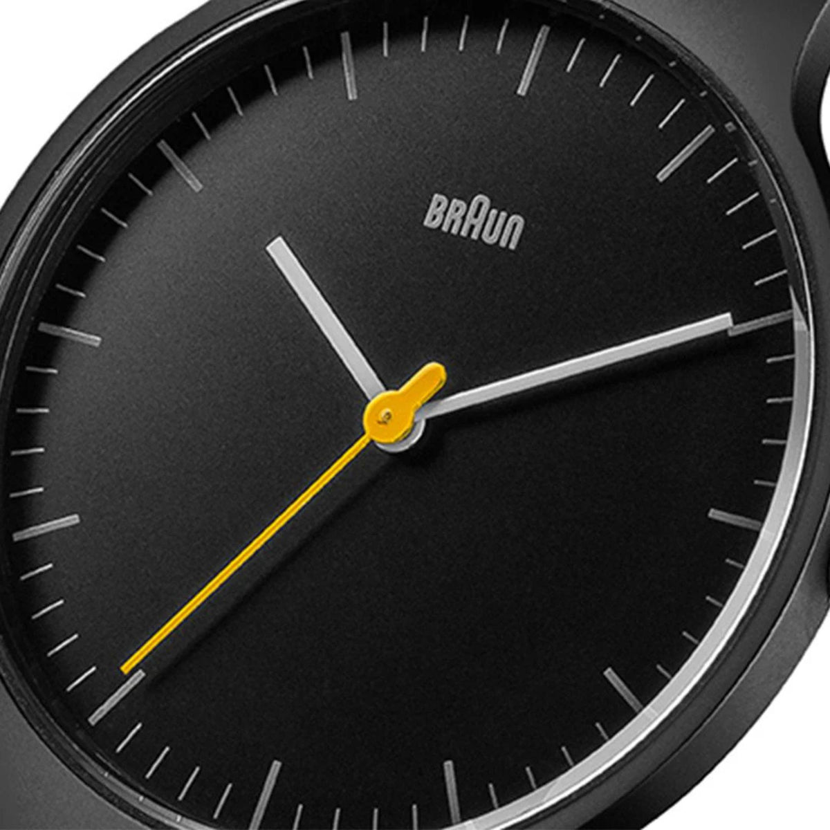Close-up of black watch dial with yellow hour marker hand and baton indices