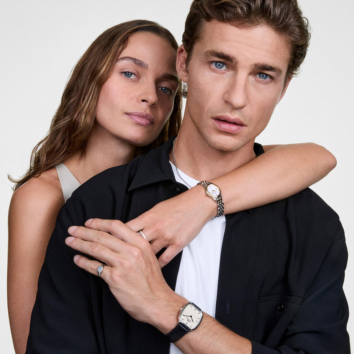 Two-tone watches on couple's wrists, white dials with Roman numerals
