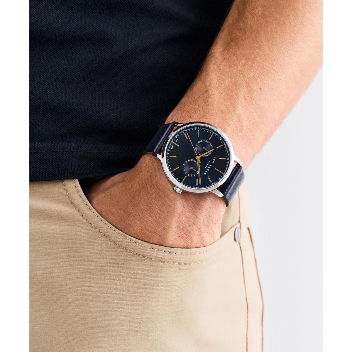 Men's watch on wrist with dark blue dial and black leather strap