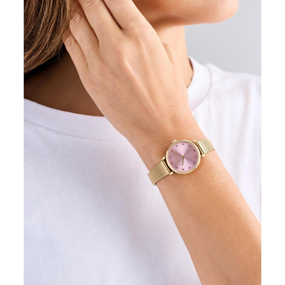 Gold-tone mesh bracelet watch with pink dial worn on wrist