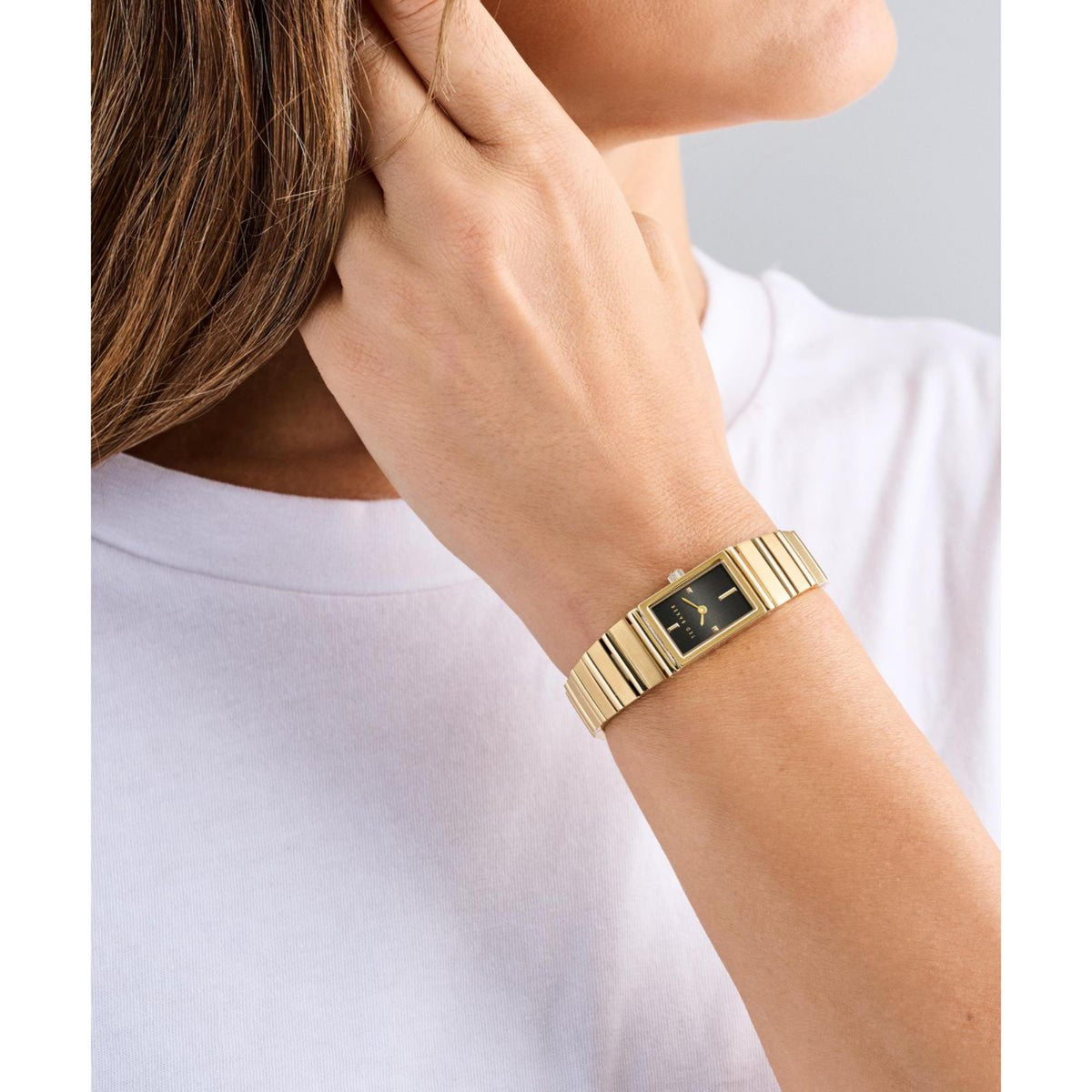 Gold-tone ladies watch on wrist with black dial and metal link bracelet