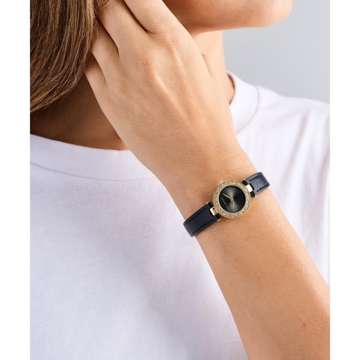 Ladies watch on wrist: black leather strap, round black dial with gold crystal bezel