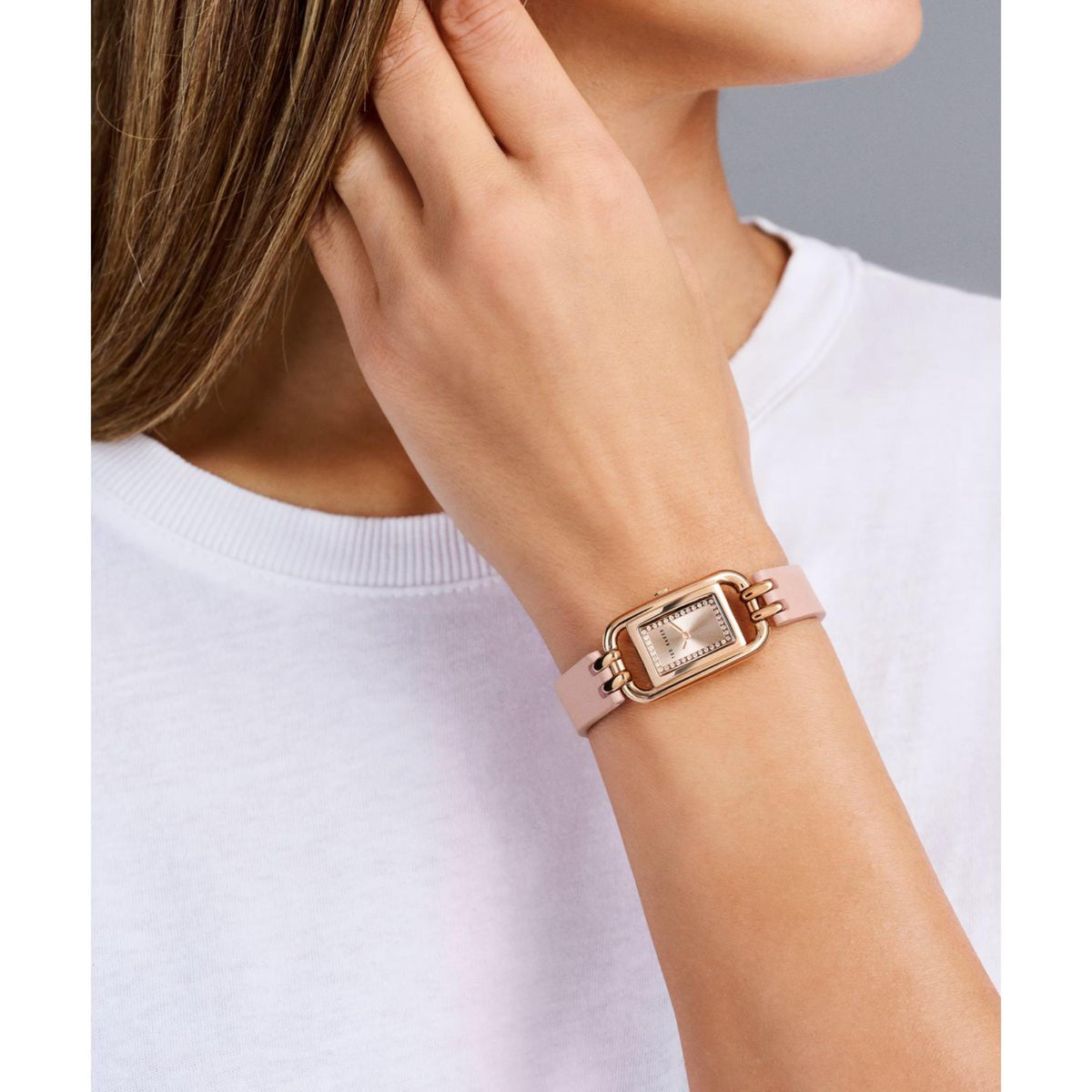 Pink leather strap watch on wrist, square rose-gold case with sparkling bezel