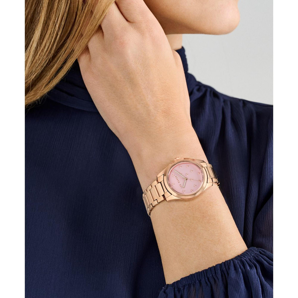 Ladies wrist watch on wrist with pink dial and rose-gold tone metal link bracelet