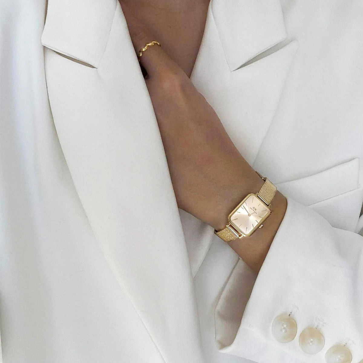 Gold-tone square watch with champagne dial on wrist, gold mesh bracelet