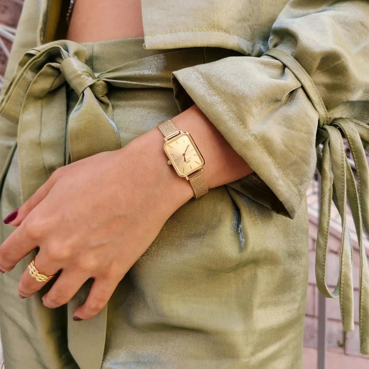 Gold-tone square watch with champagne dial on wrist, gold mesh bracelet