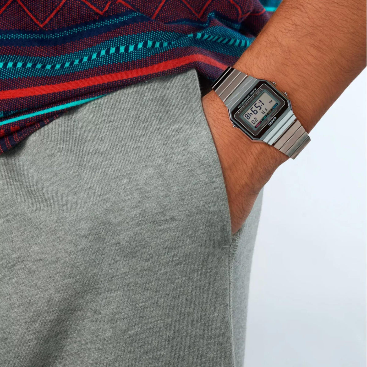 Silver digital alarm chronograph watch on wrist with rectangular LCD screen and steel bracelet