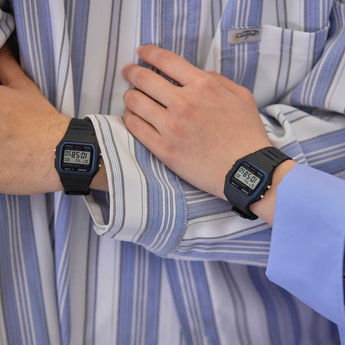 Close-up of Casio Vintage Retro Digital Resin Strap Unisex Watch F-91W-1XY showing the watch worn on both wrists of a couple