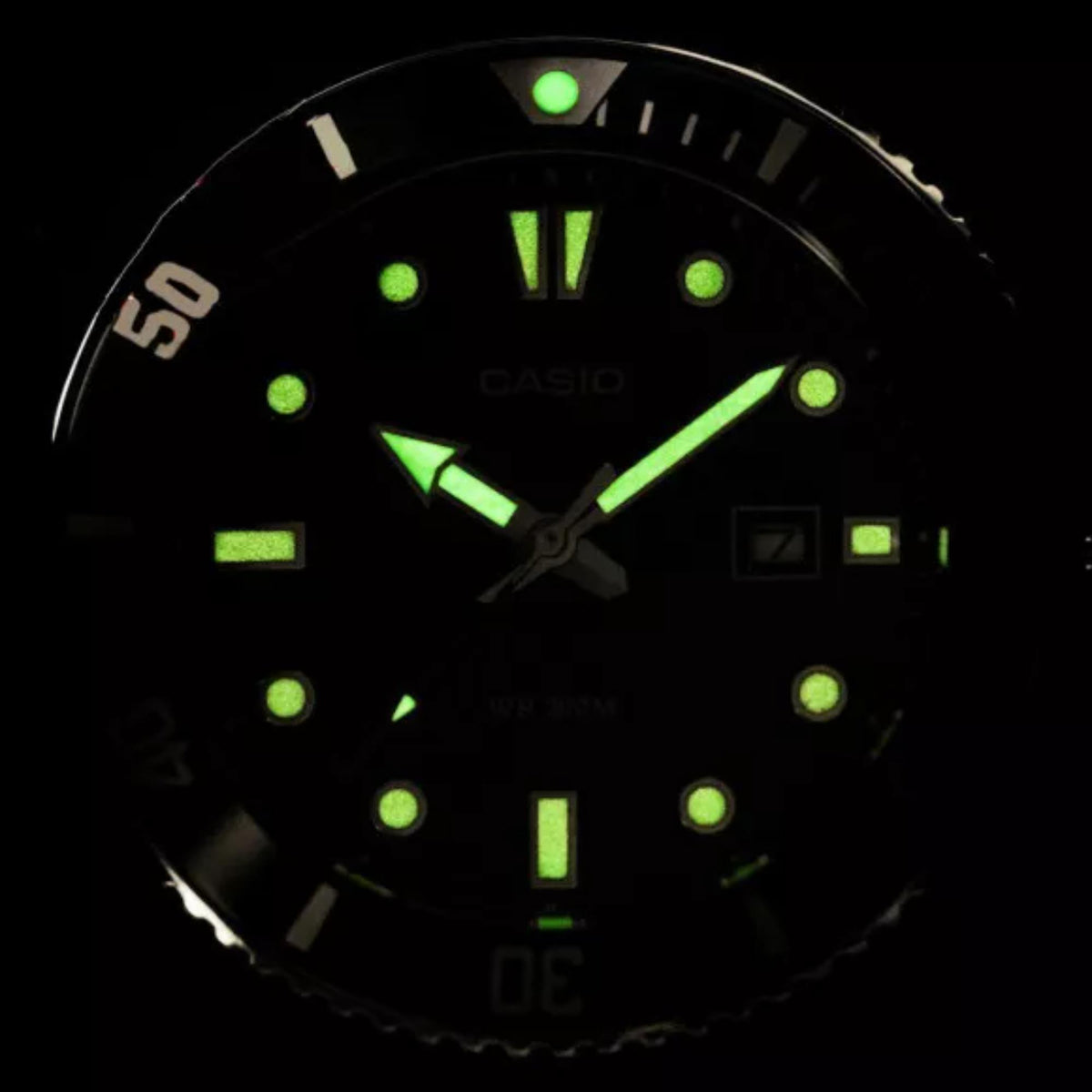 Casio men's watch face with glowing green lume markers on black dial, night display