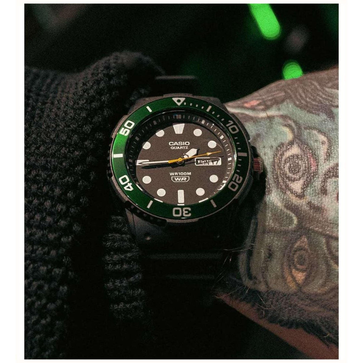 On-wrist close-up of the Casio Vintage Diver MRW-230H-1E3VEF watch highlighting the black dial, green bezel ring, and resin strap