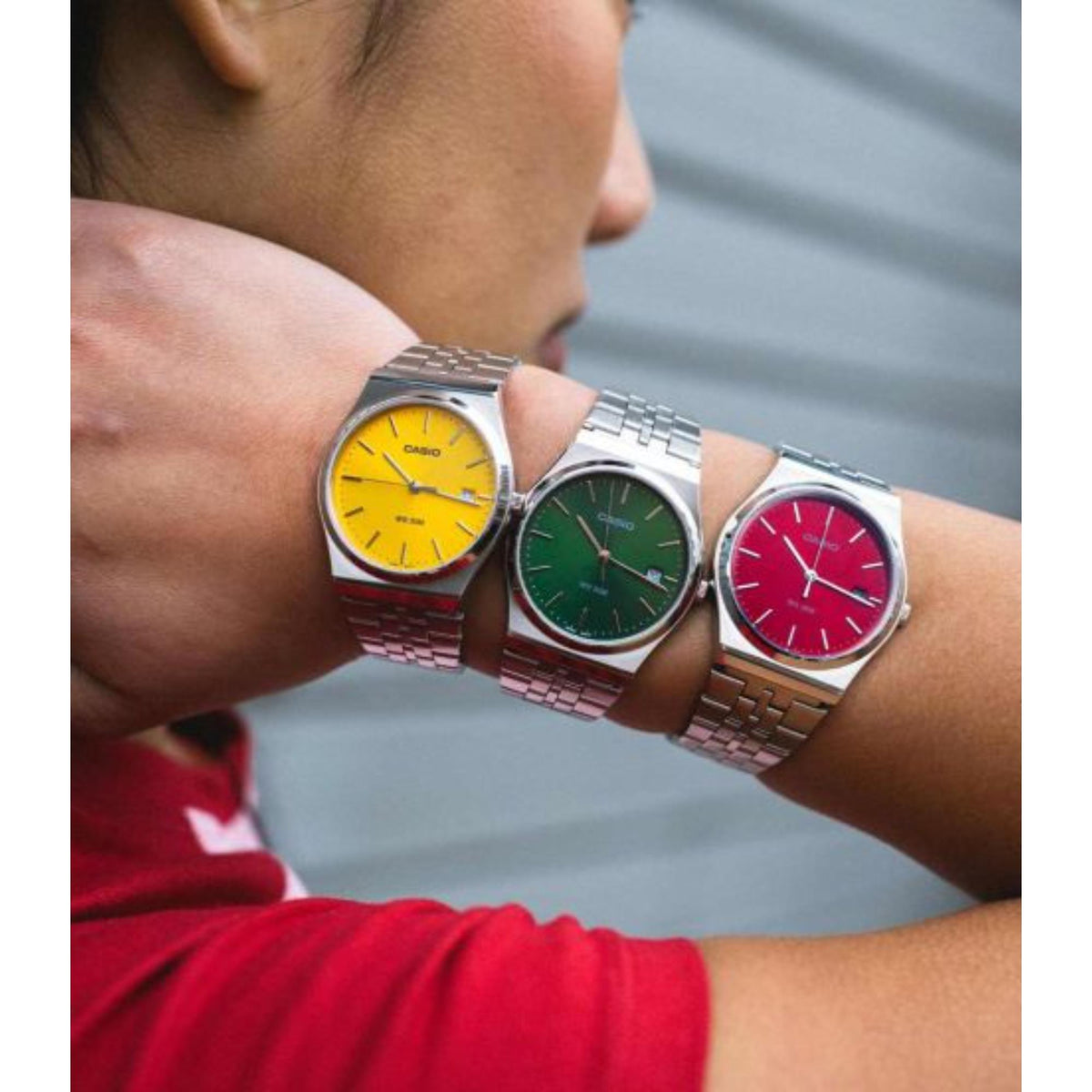 Men's red dial watch on wrist with silver case and metal link bracelet