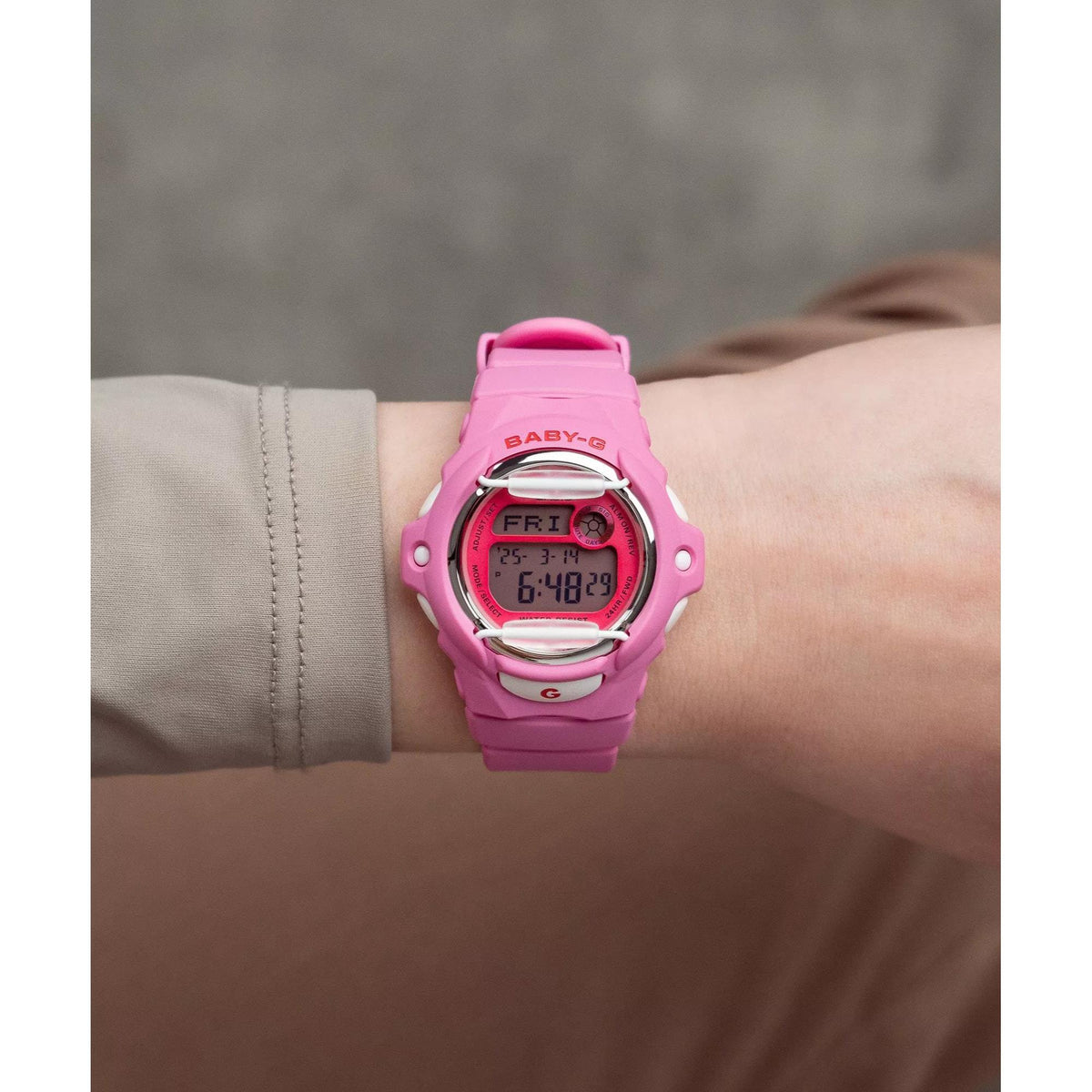 Pink Casio BABY-G digital watch on wrist, round LCD face and side buttons.
