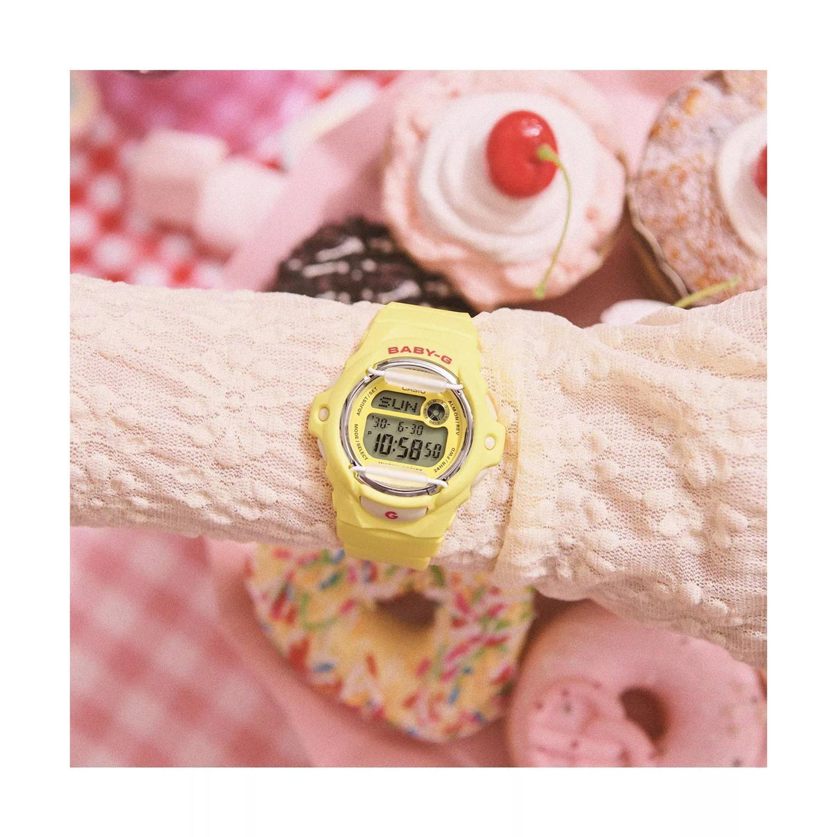 Stylized flat lay showing the Casio Baby-G BG-169CH-9ER pastel yellow digital watch surrounded by sweet treats