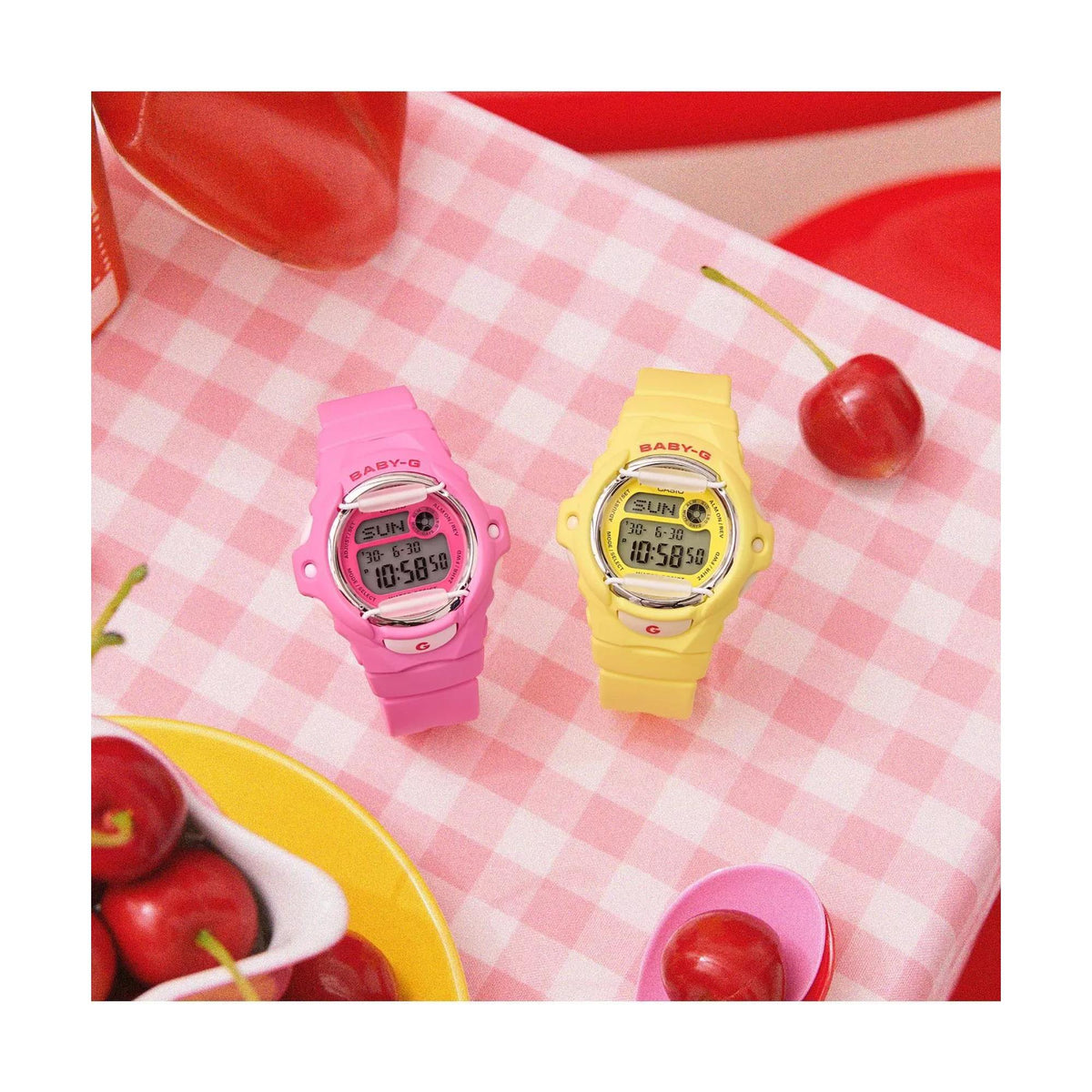 The yellow Casio Baby-G BG-169CH-9ER digital watch styled alongside a matching pink edition on a gingham surface