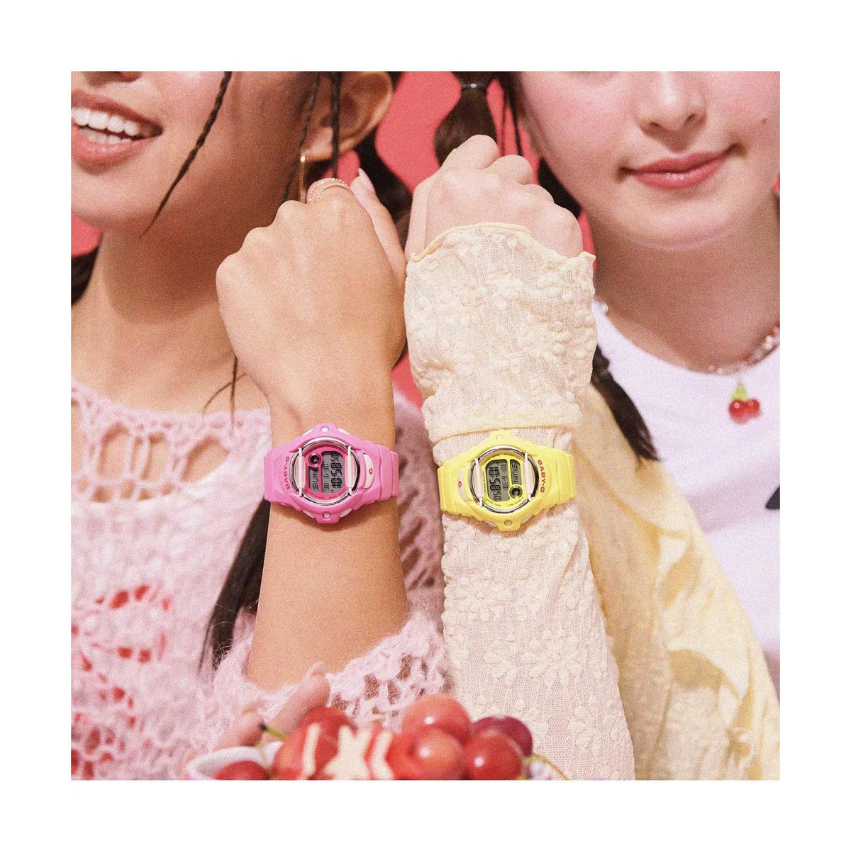 Two models displaying the yellow Casio Baby-G BG-169CH-9ER watch and a pink counterpart side-by-side on their wrists