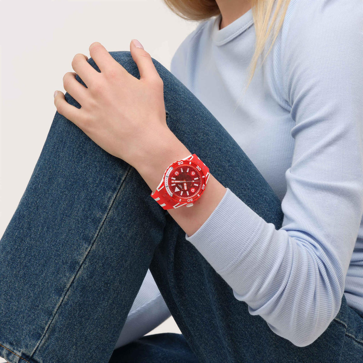 Red dive watch worn on wrist with red dial and silicone strap.