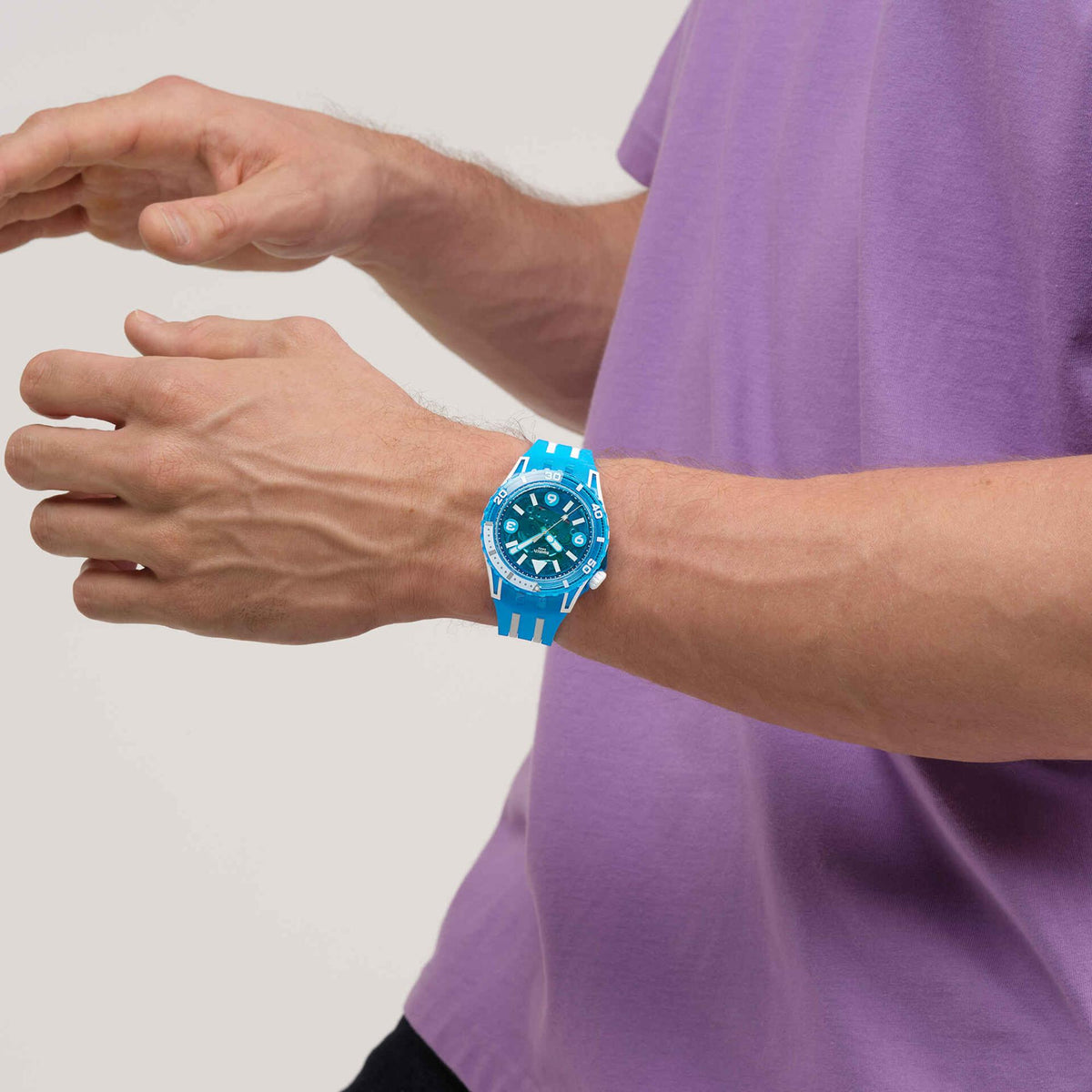 Blue silicone-strap watch on wrist, blue dial with white hour markers and bezel ring