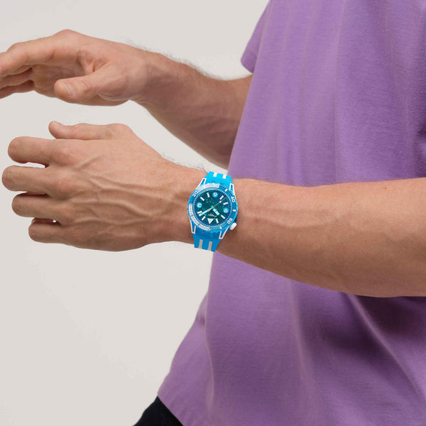 Blue silicone-strap watch on wrist, blue dial with white hour markers and bezel ring