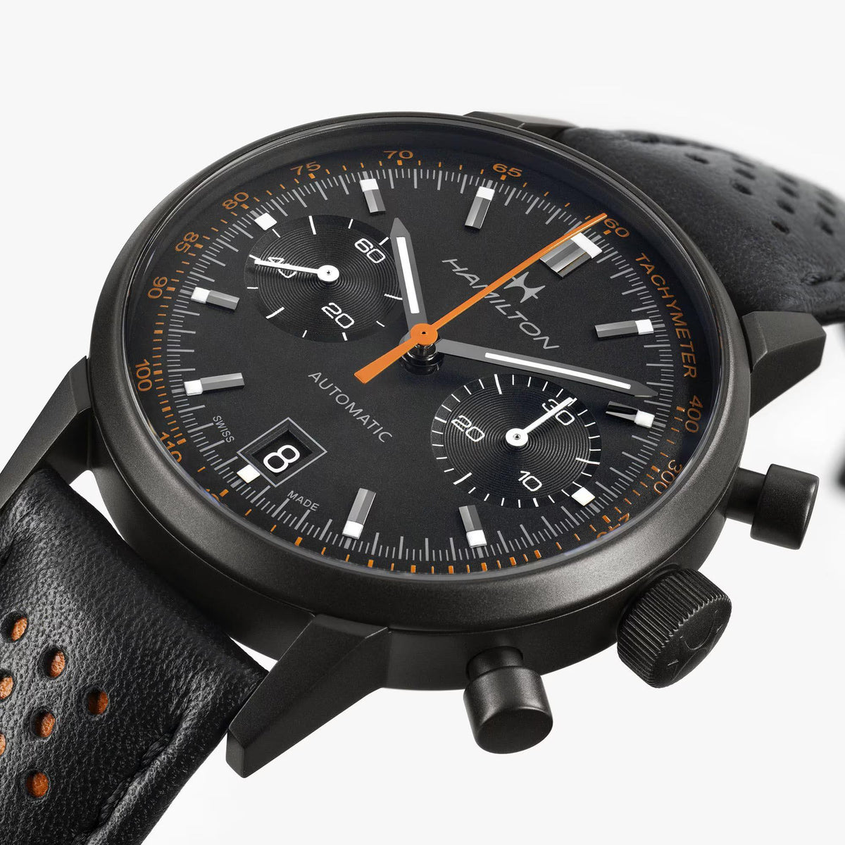 Black dial chronograph watch with orange hands, tachymeter markings, and leather strap