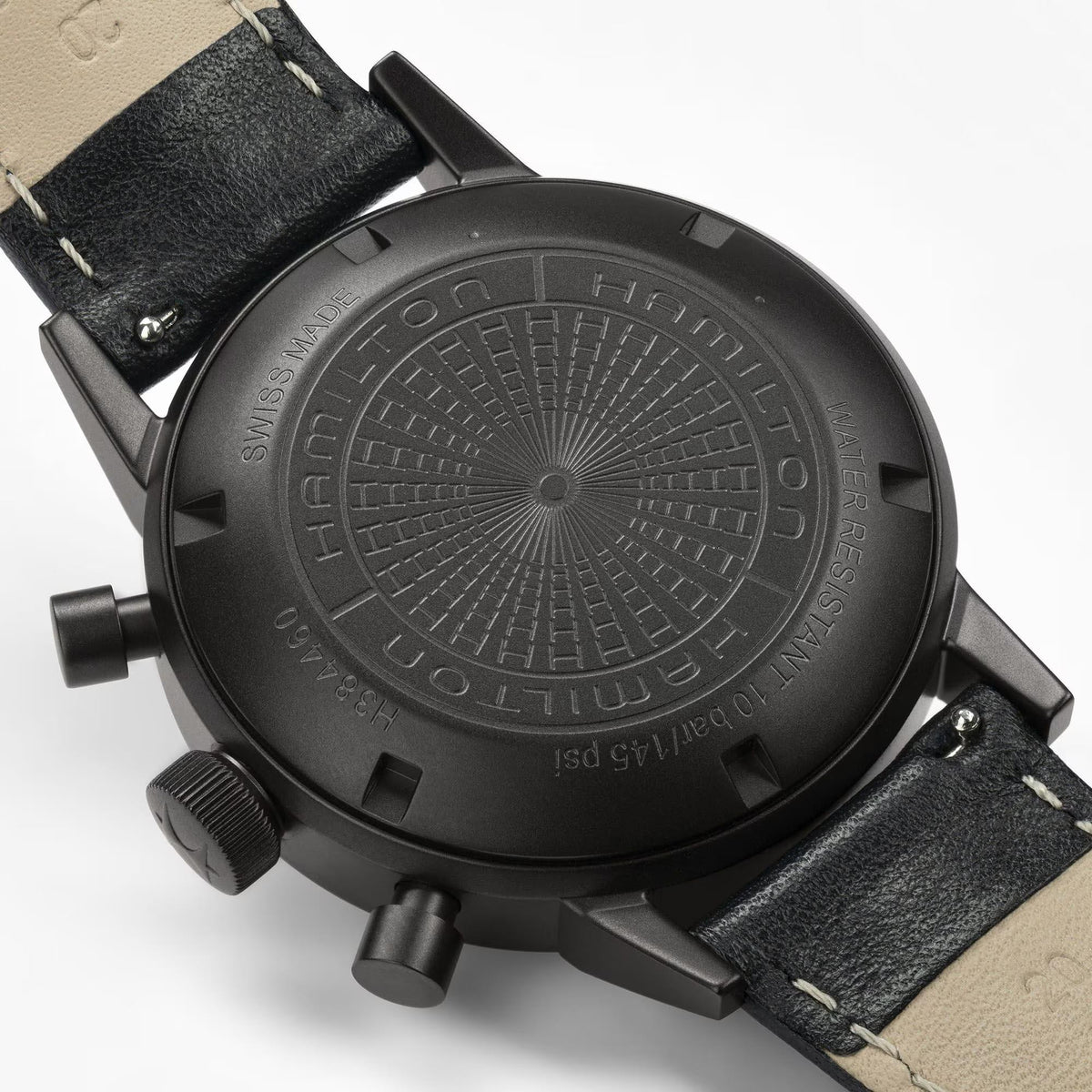 Black watch case back with engraved details and leather strap, chronograph style