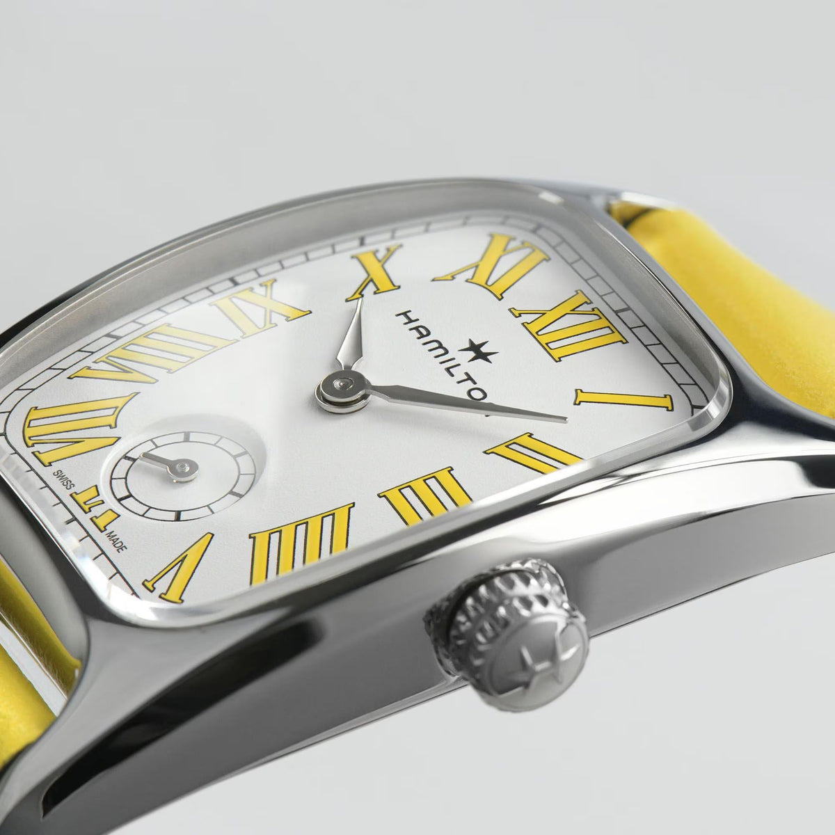 Close-up quartz watch face, white dial with Roman numerals and yellow leather strap