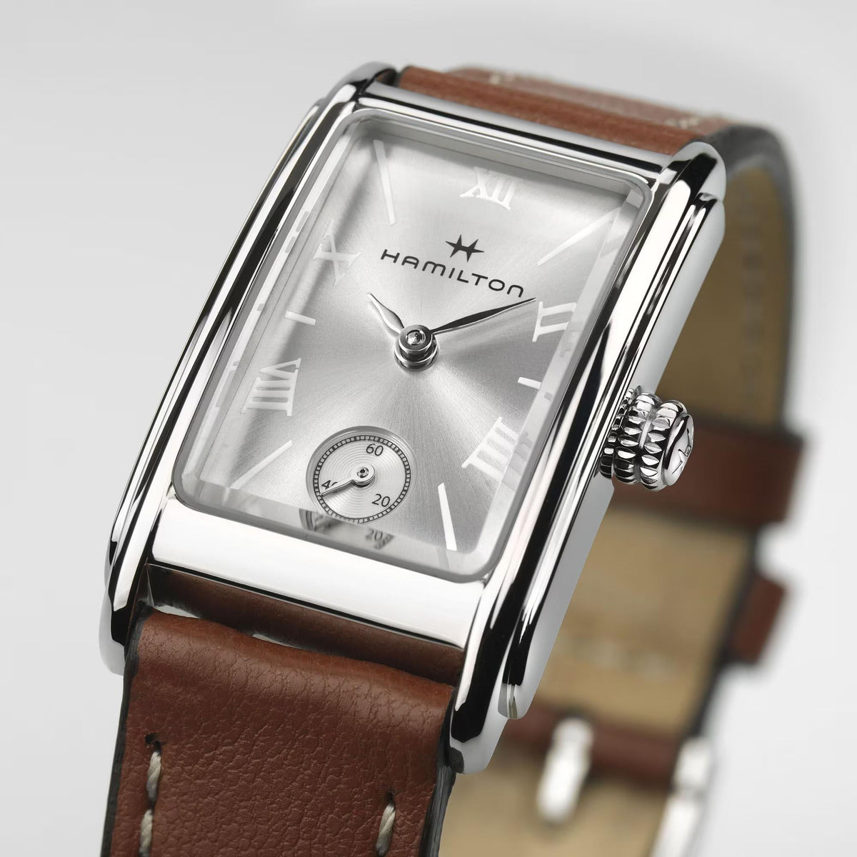 Silver-toned square watch with brown leather strap and Roman numeral dial