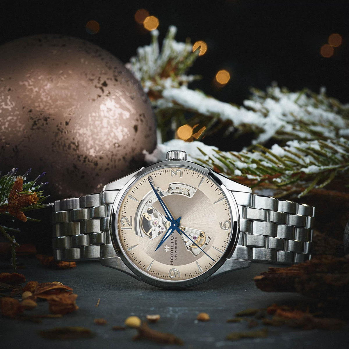 Hamilton Jazzmaster H32705121 42mm mens timepiece styled in a holiday setting, showing a beige cutout dial and blue hands