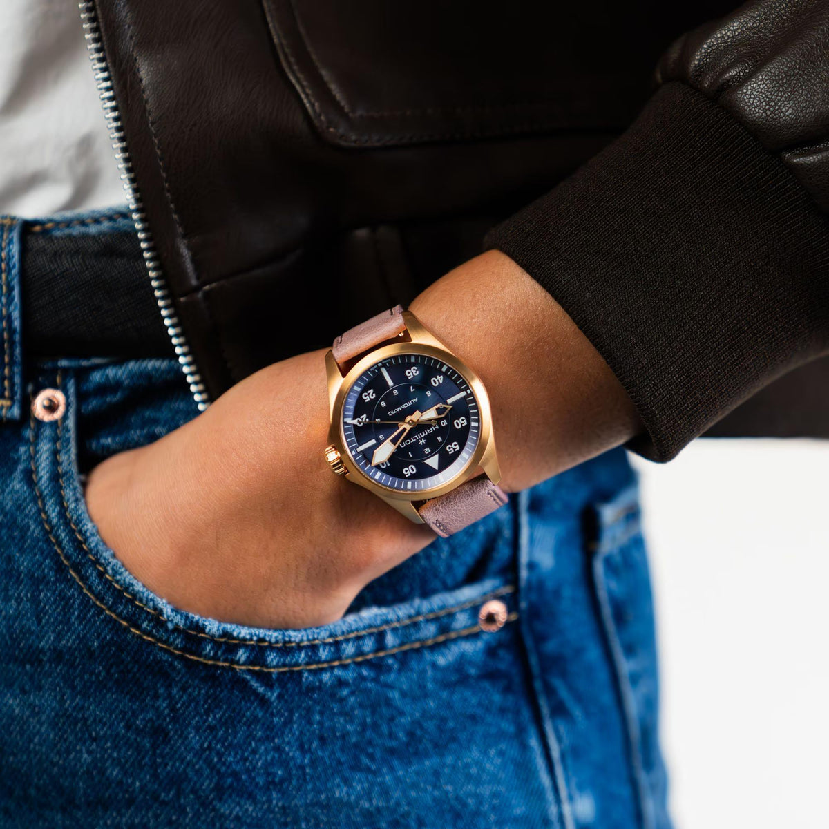 Hamilton watch on wrist with mauve leather strap and dark blue dial and gold markers