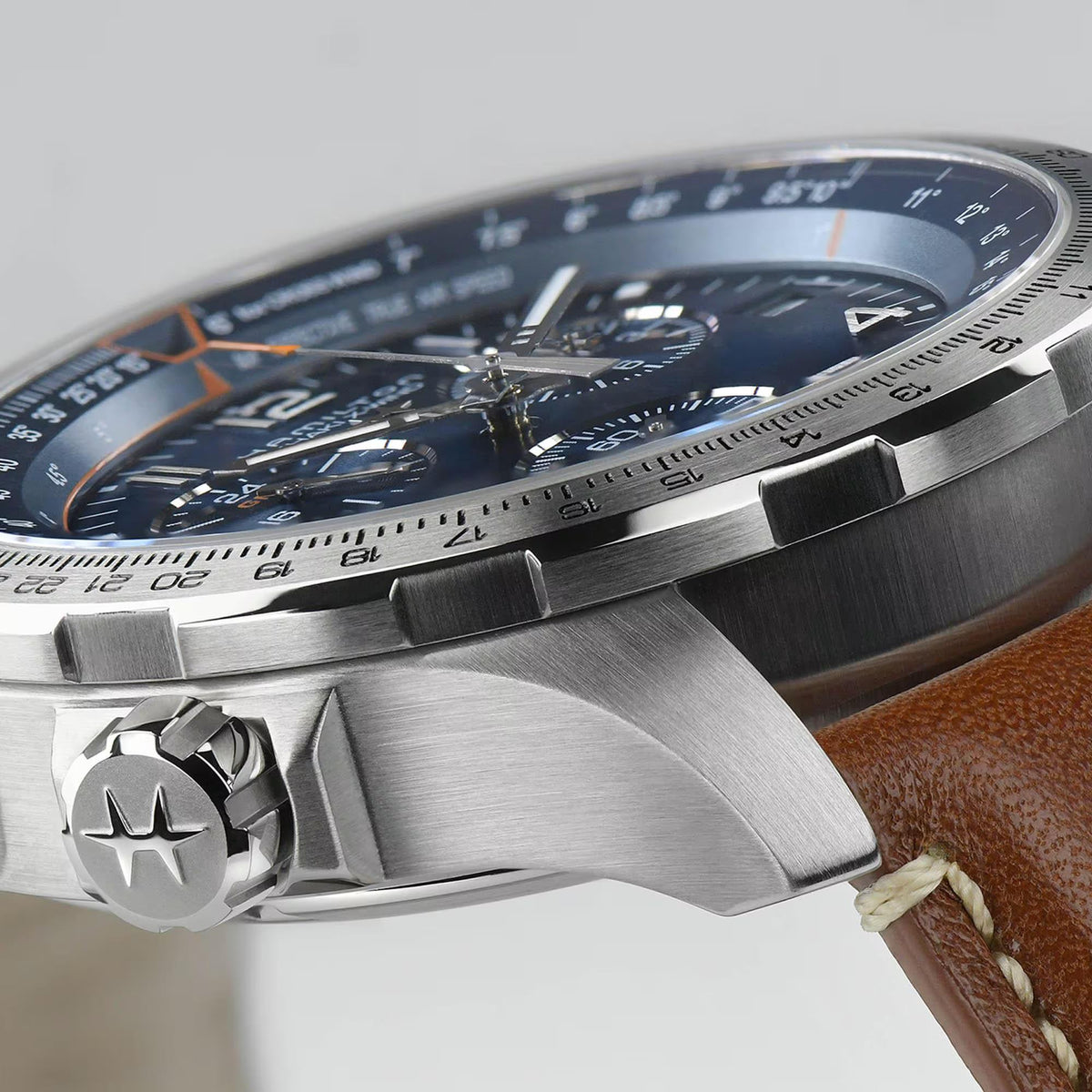 Stainless watch case detail with crown and bezel, blue dial viewed from the side
