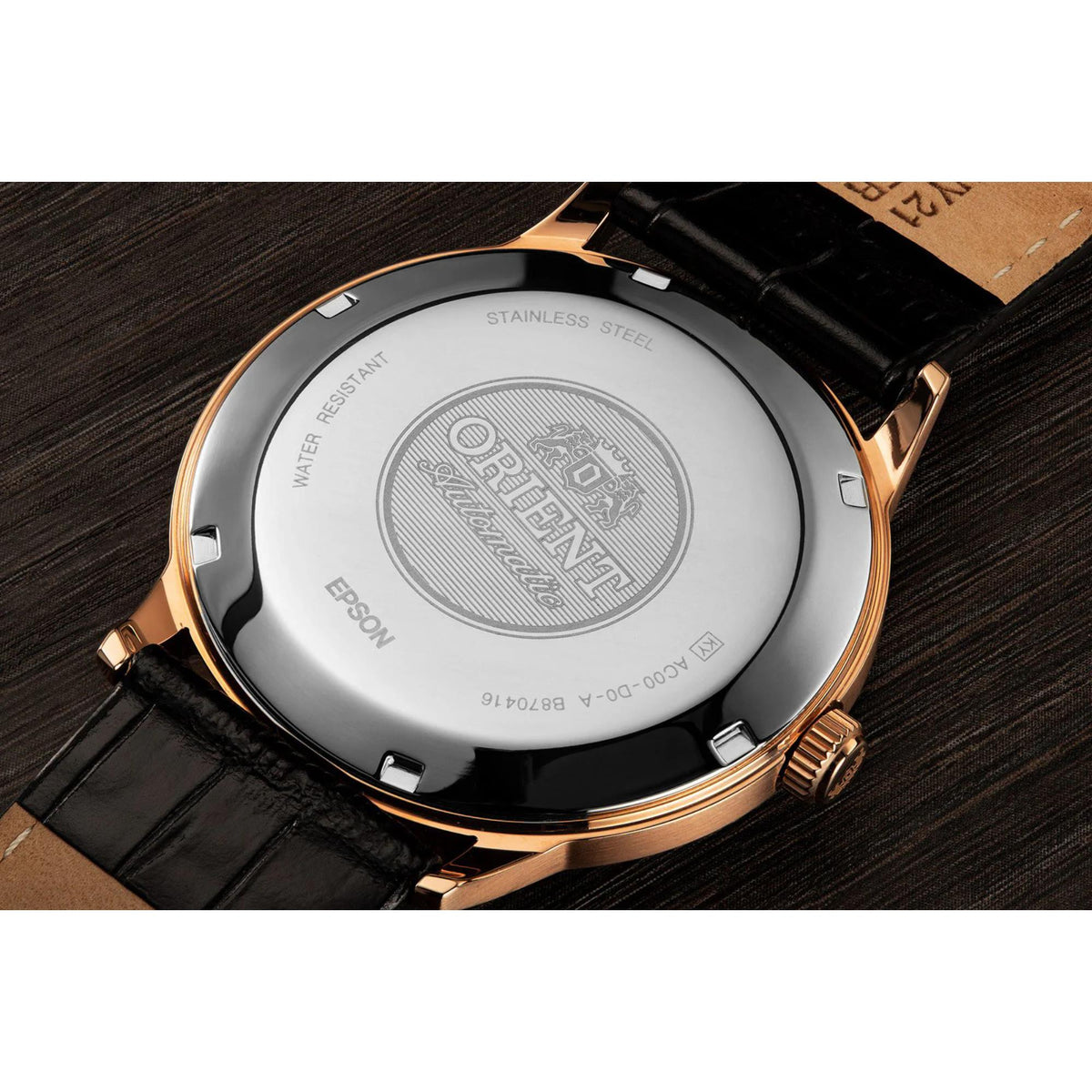 Back of stainless steel watch case with engraved 'ORIENT' and black leather strap.