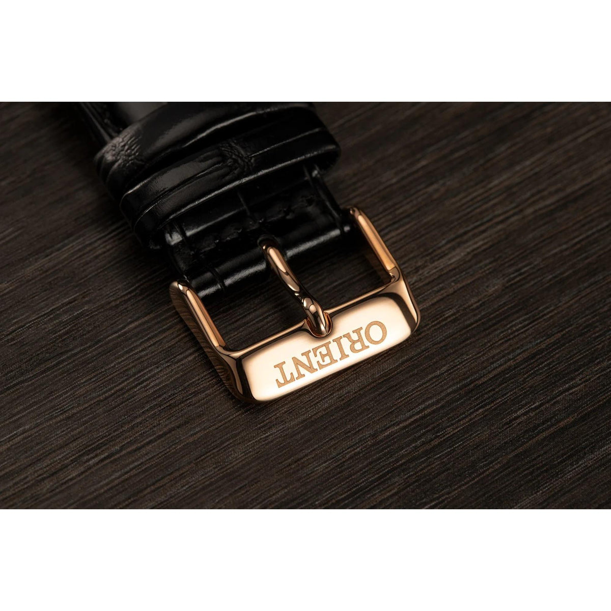 Black leather watch strap with rose-gold buckle and metal pin.