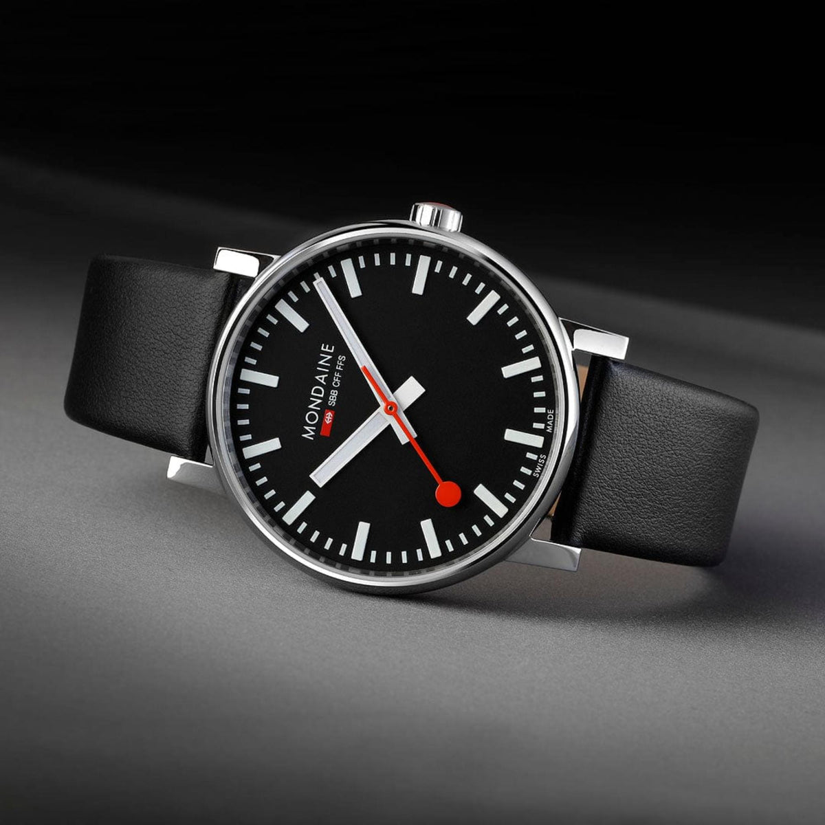Mondaine Evo2 MSE.43120.LB minimalist watch angled flat lay on dark background highlighting red second hand