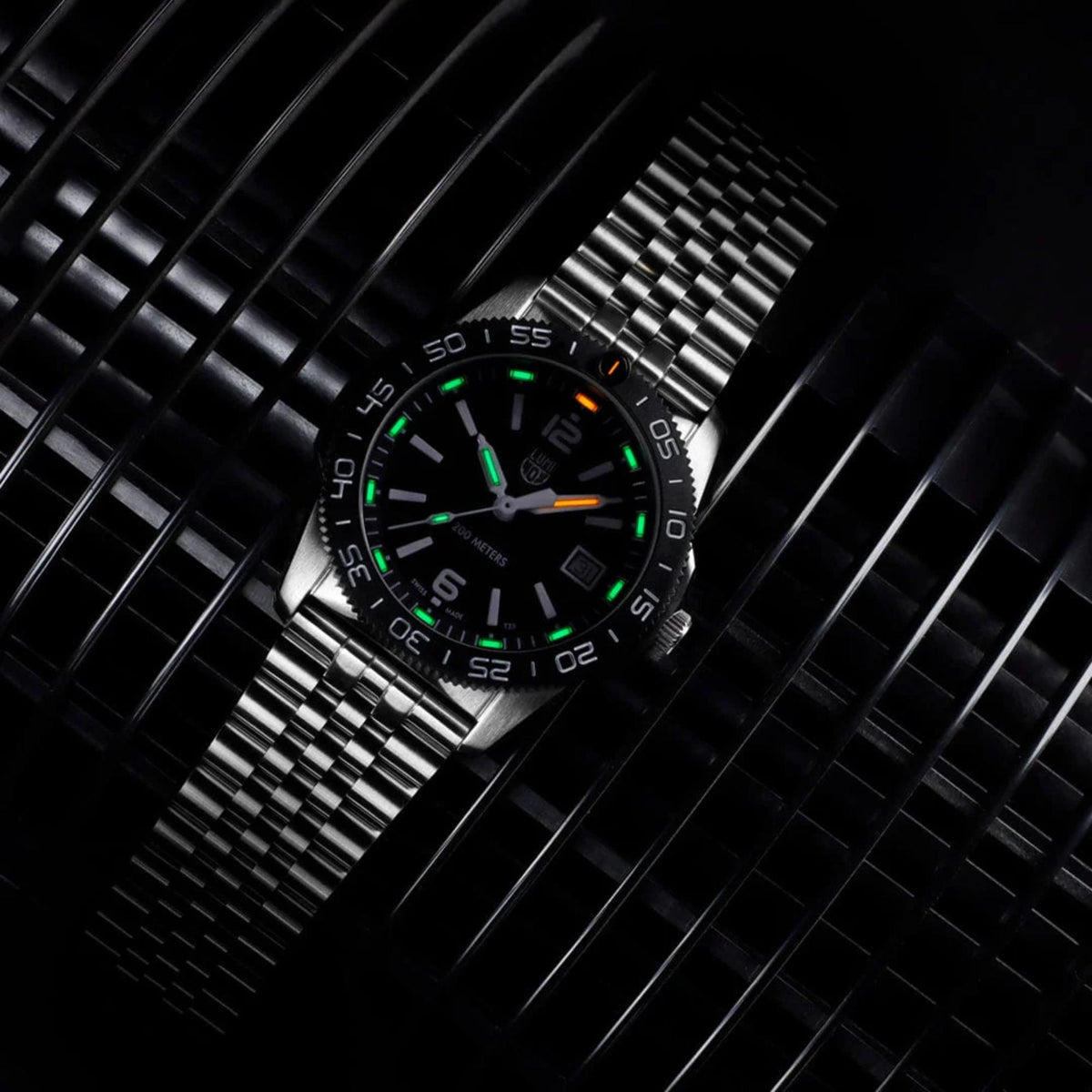 Luminox Pacific Diver XS.3122M angled low light view displaying illuminated gas tubes against black dial and steel bracelet