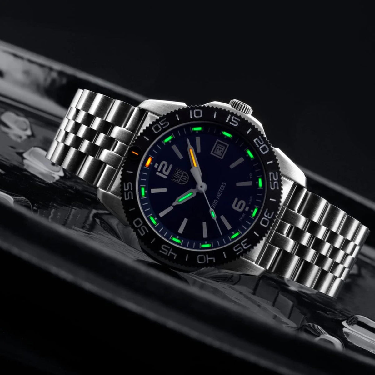 Steel dive watch with blue dial, green accents, and stainless bracelet.