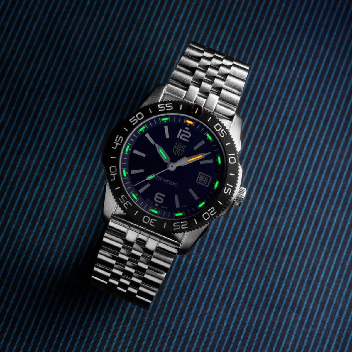Stainless steel dive watch, blue dial with luminous green markers and metal bracelet.