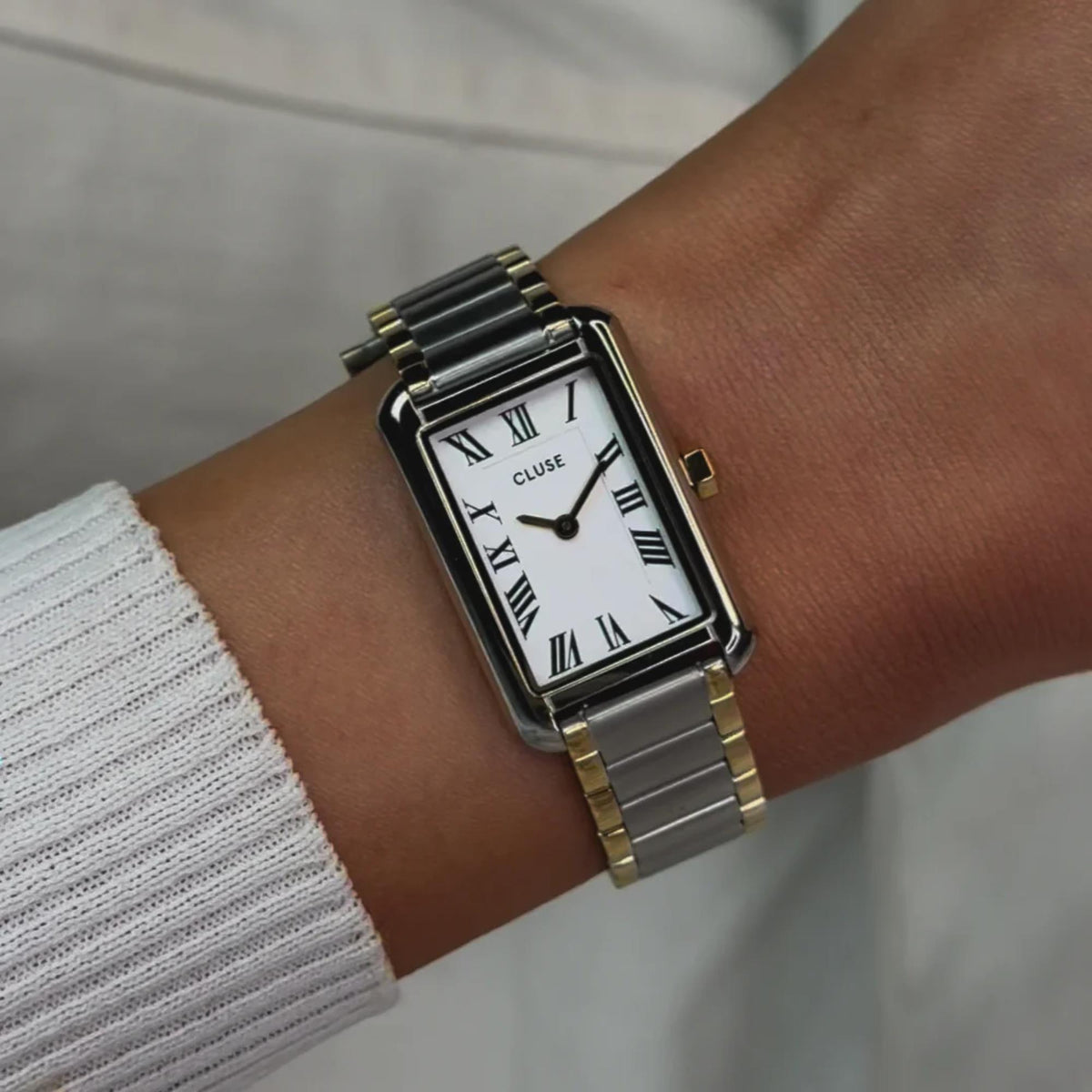 Two-tone steel wristwatch with white dial, Roman numerals, and metal bracelet on wrist