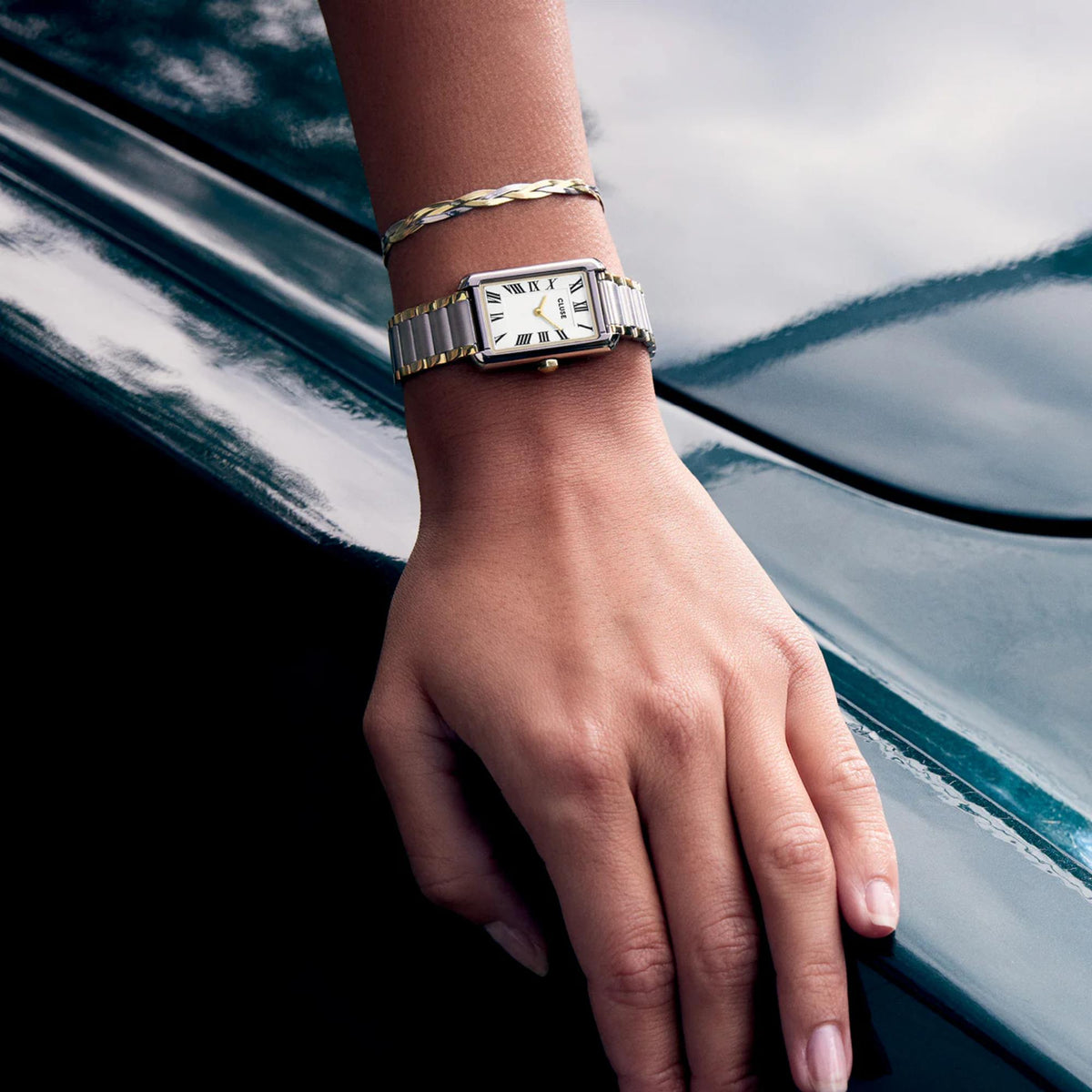 Two-tone steel watch with white dial and Roman numerals on wrist