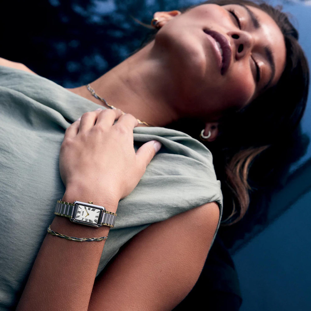 Two-tone steel watch on a woman’s wrist, white dial with Roman numerals