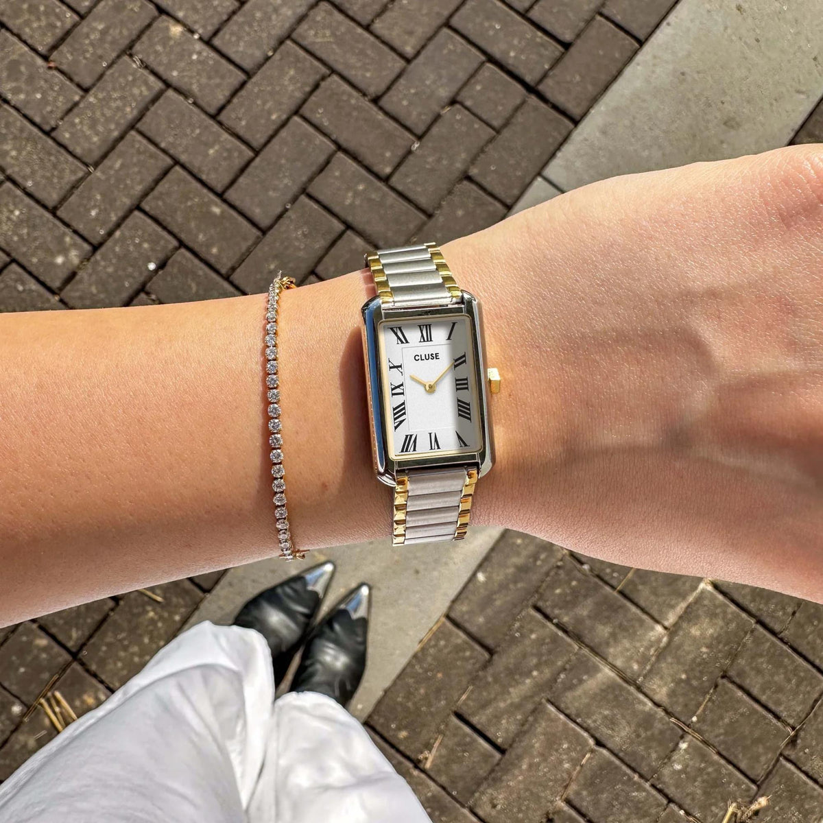 Two-tone steel watch with white dial and Roman numerals on wrist
