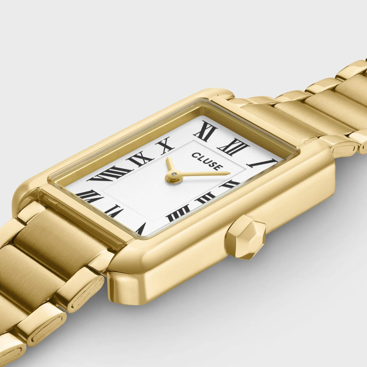 Gold-tone rectangular watch with white dial, Roman numerals, and link bracelet close-up