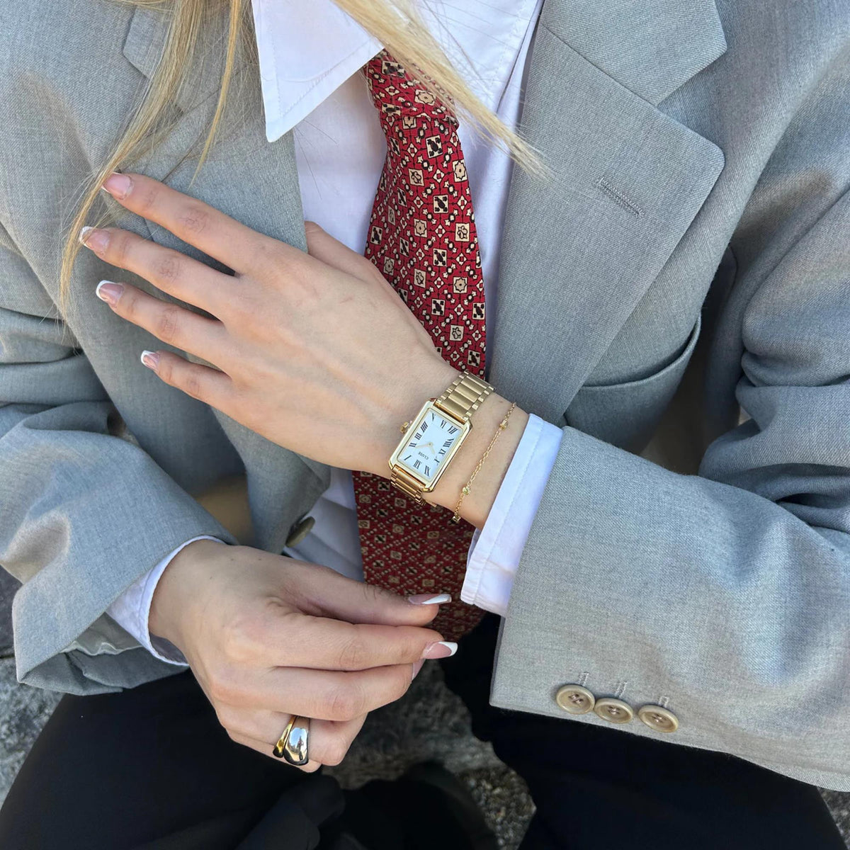 Gold-tone rectangular watch on wrist with white dial and Roman numerals
