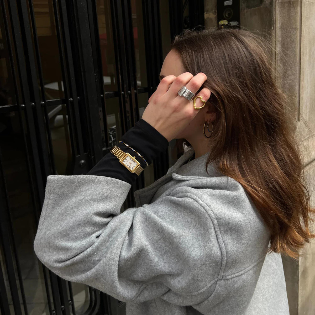 Gold-tone rectangular watch on wrist with white dial