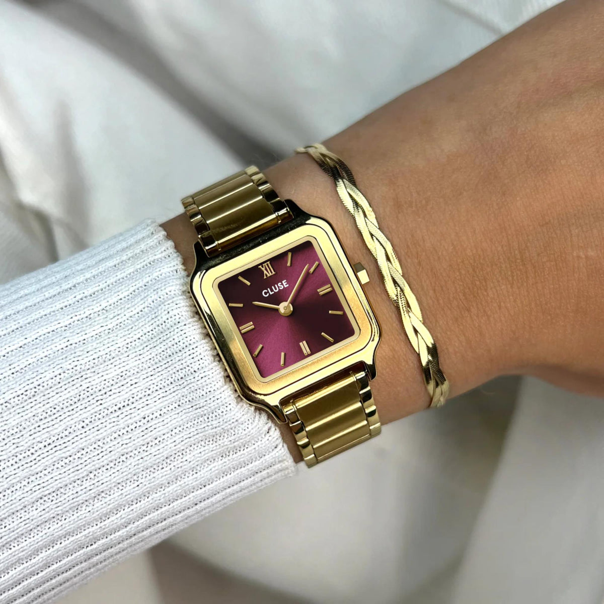 Square quartz wristwatch with gold-tone link strap and purple-red dial