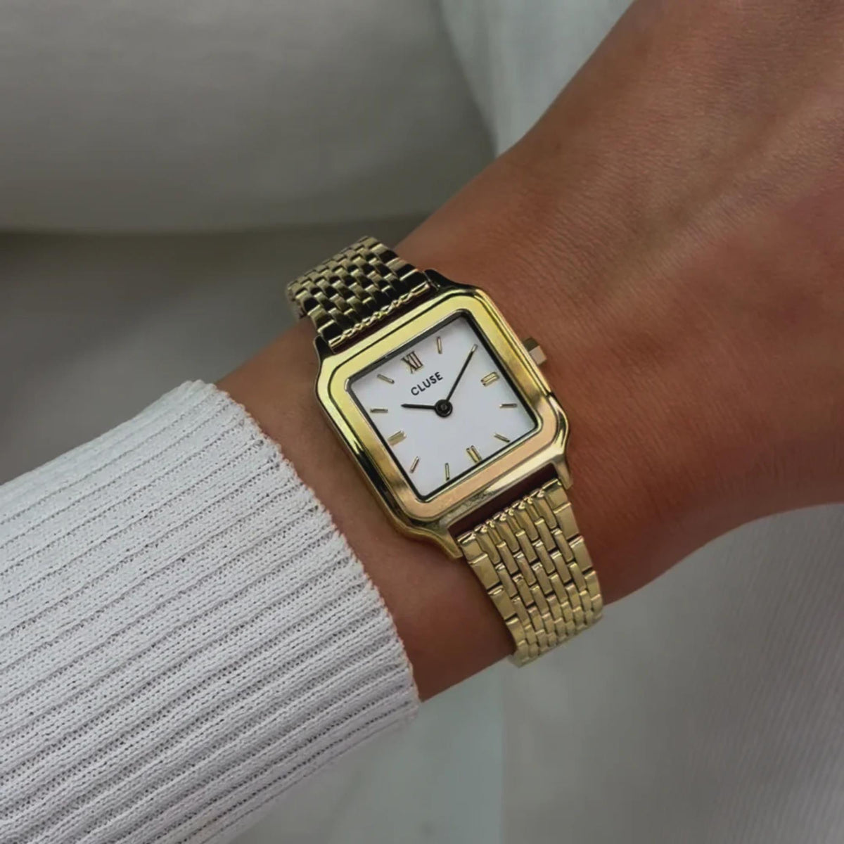 CLUSE women’s square quartz watch with gold-tone case and white dial on wrist
