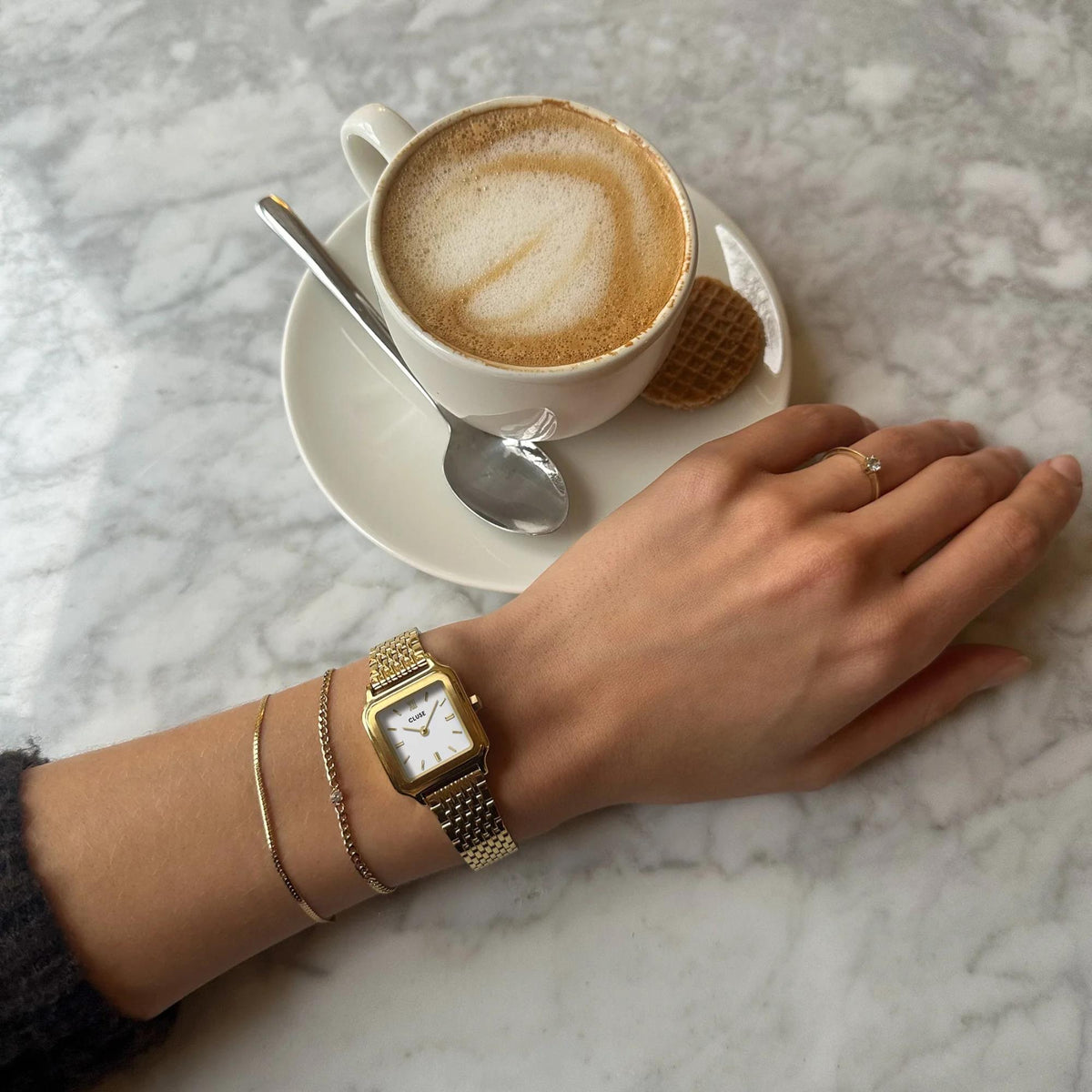 CLUSE women’s gold-tone square quartz watch with white dial on wrist