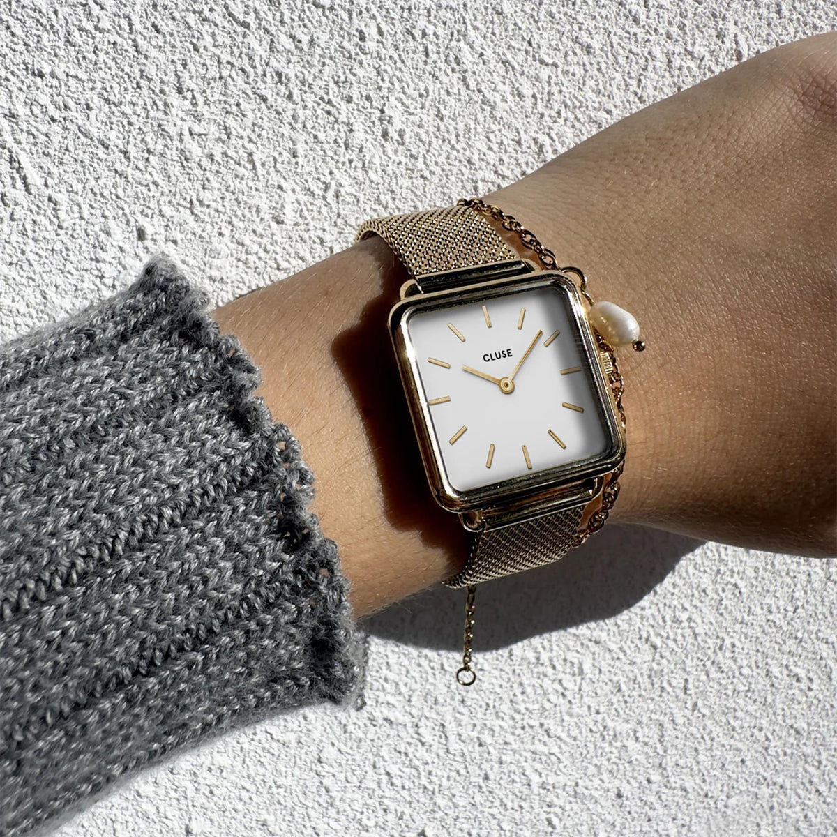 Women's square quartz watch on wrist, white dial with gold indices and mesh bracelet
