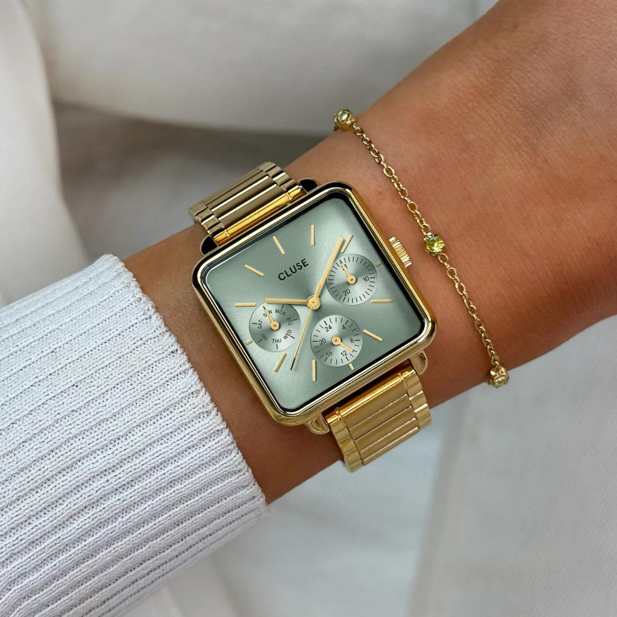 Gold-tone square chronograph watch on wrist, light green dial with three subdials