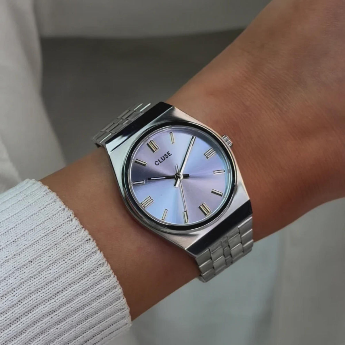 Women's steel strap watch on wrist, light blue dial with gold markers and CLUSE logo
