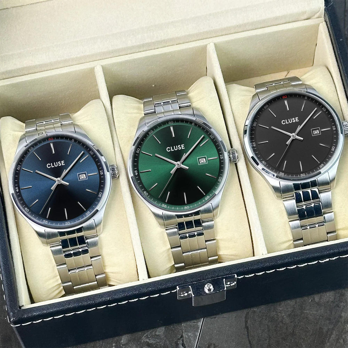 Three men's watches in a gift box, showing blue and black dials with steel bracelets.