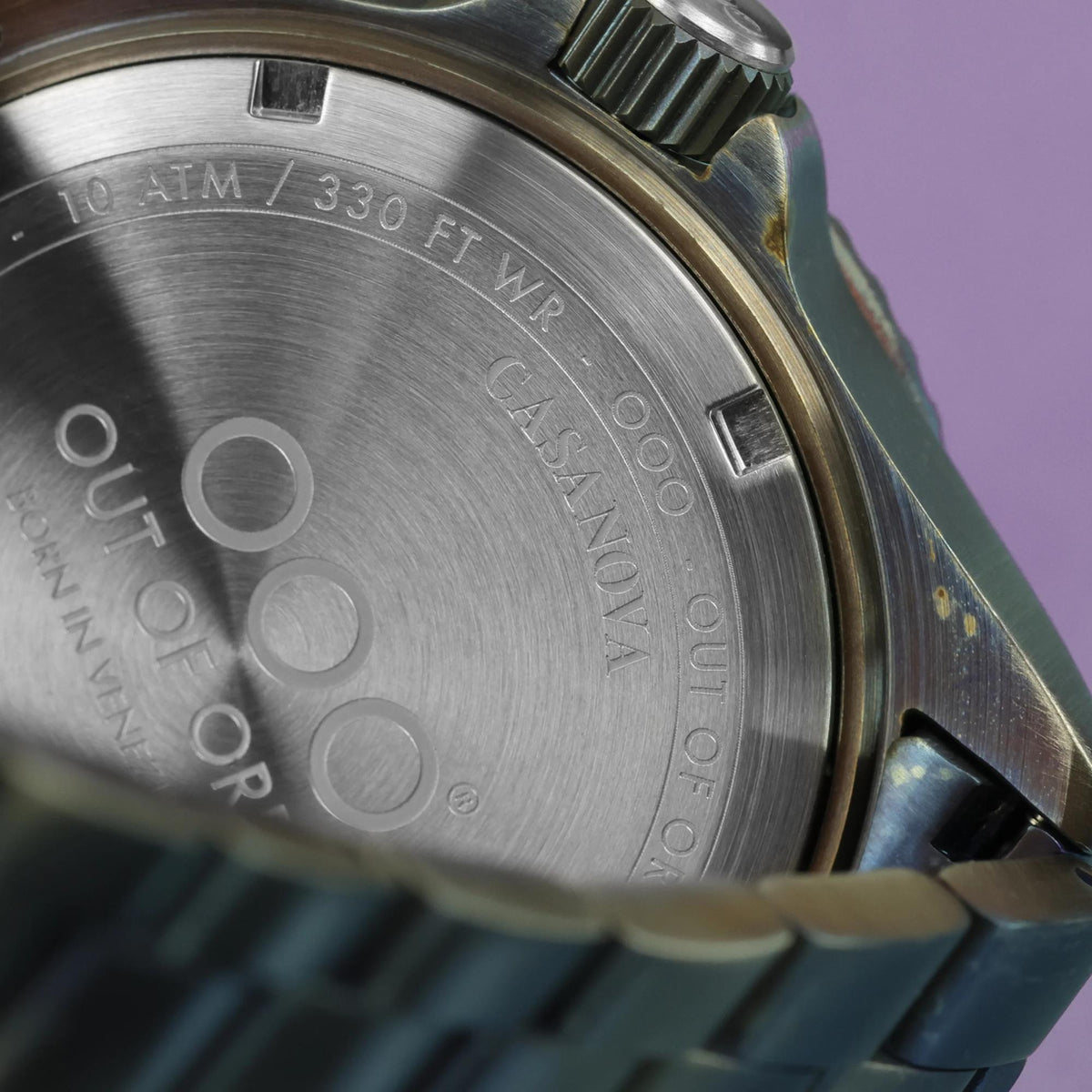 Men's watch case back close-up with 100 ATM and 330 ft WR water resistance text
